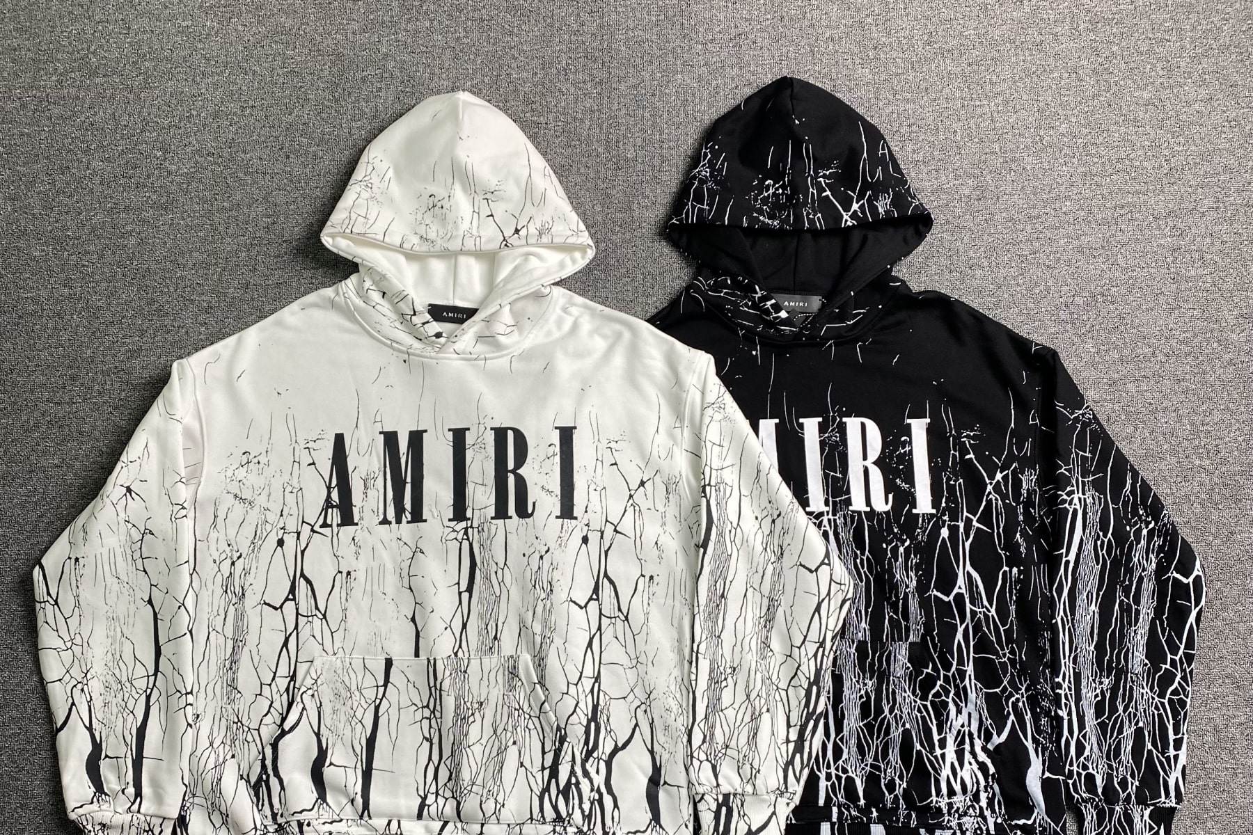 Two Amiri hoodies. A white one (left) and a black one (right)